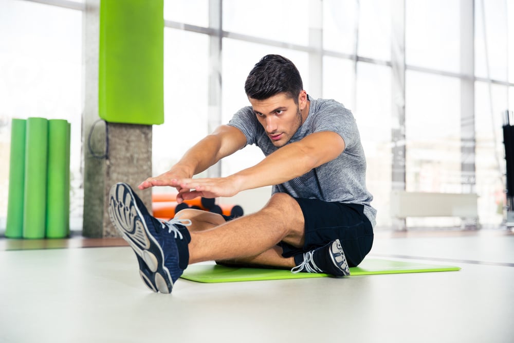 Portrait of a fitness man doing stretching exercises at gym